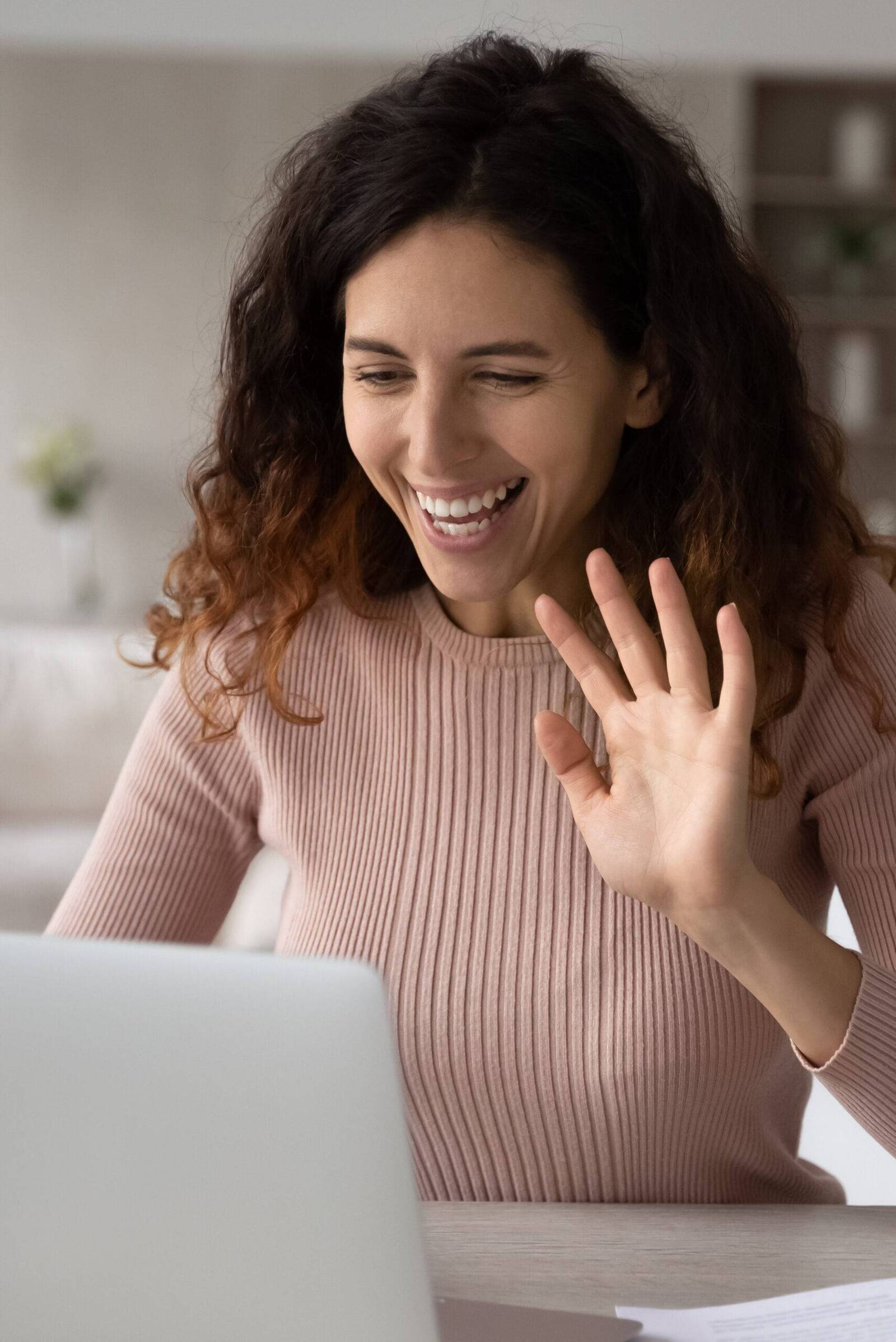 Woman waving to another person in a video call