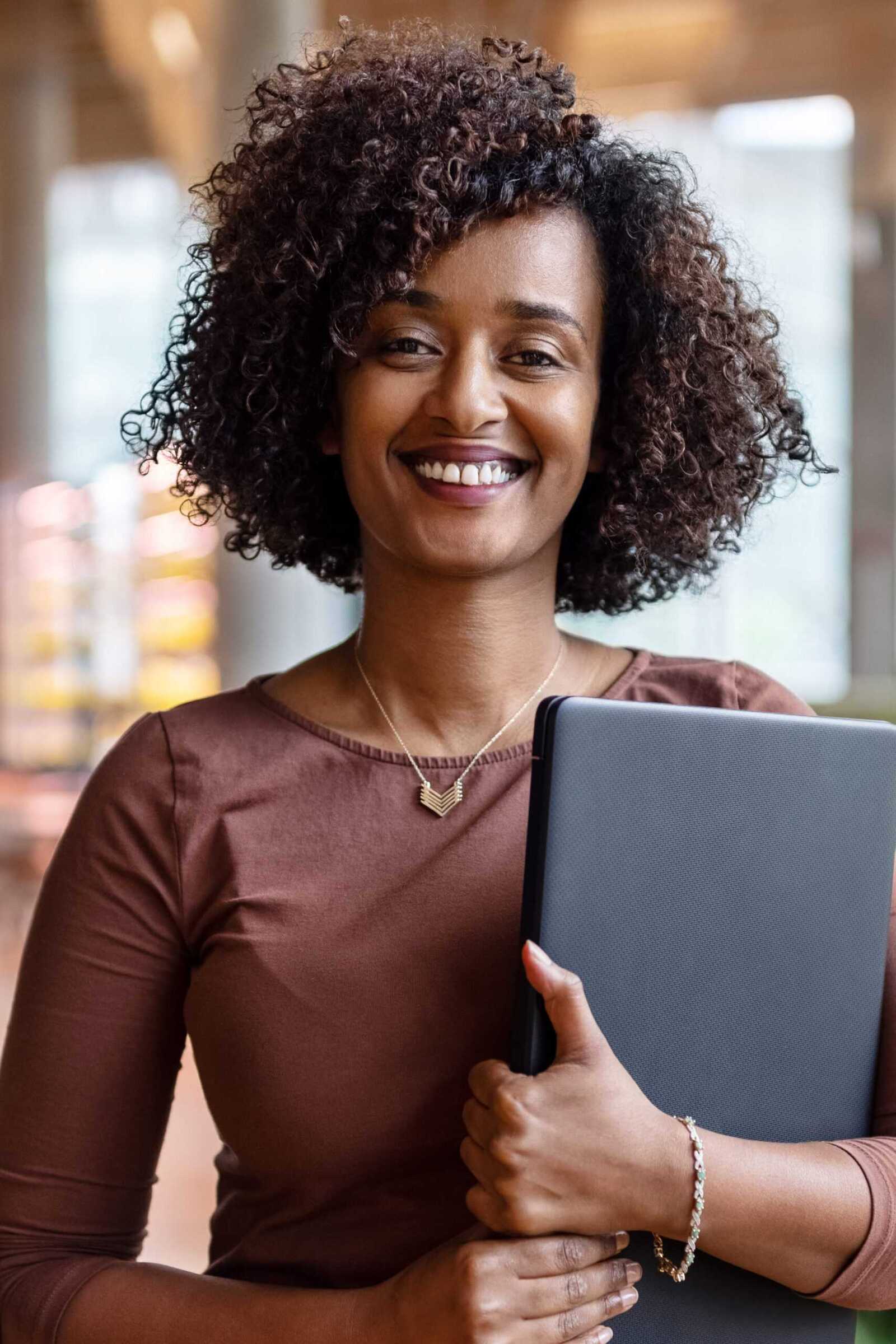 Smiling woman holding her laptop